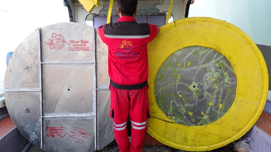 Commercial diver from Blue Sea Services performing underwater blanking and de-blanking of an overboard valve using a custom cofferdam on a vessel hull in Karachi Port.